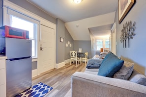A compact living space with a kitchenette, a dining area, and a seating area with a sofa and chairs.