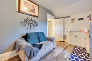 A living room with a grey sofa, a blue throw blanket, and a patterned rug.