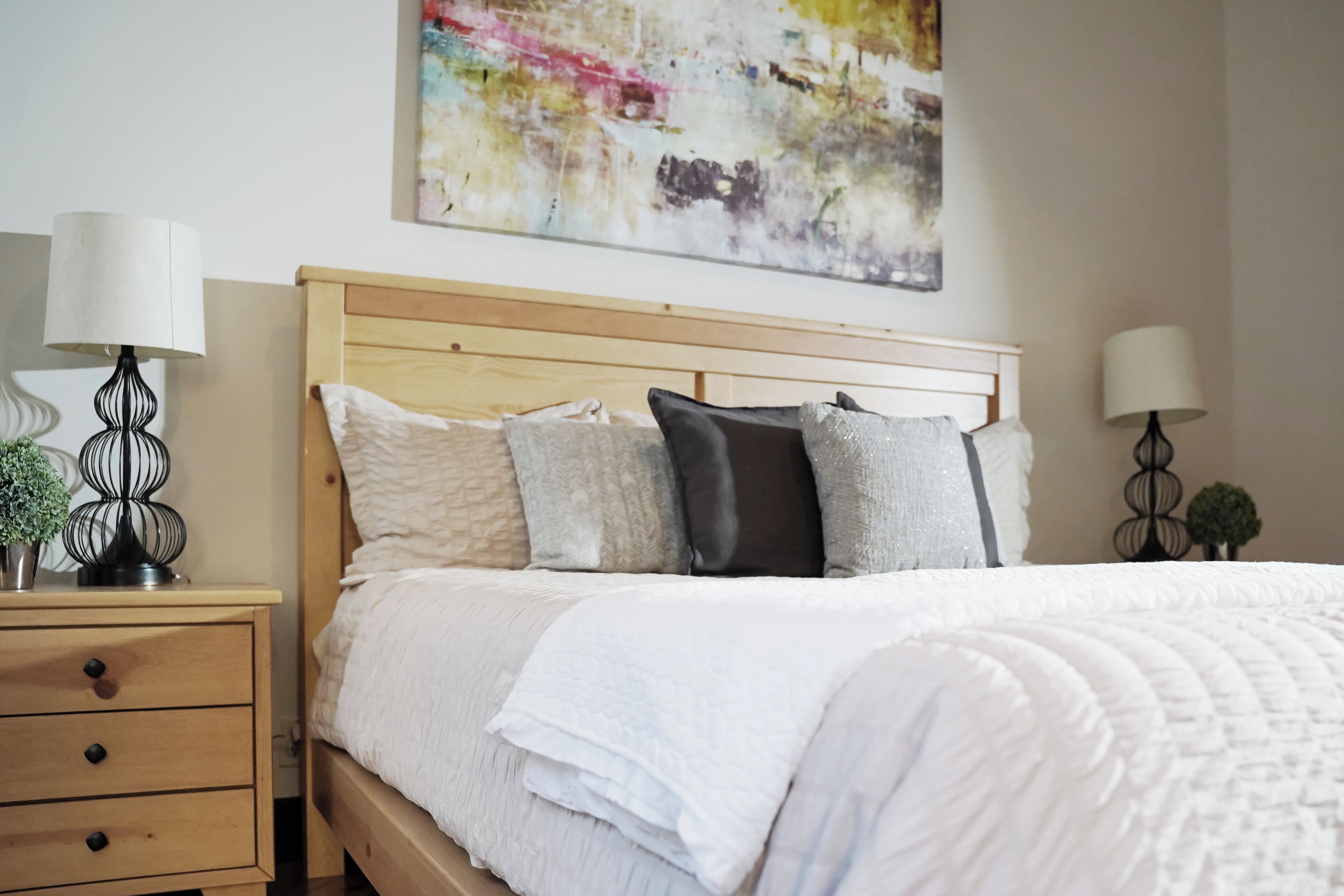 A bedroom with a wooden headboard, a white quilted bedspread, and two bedside tables with lamps.