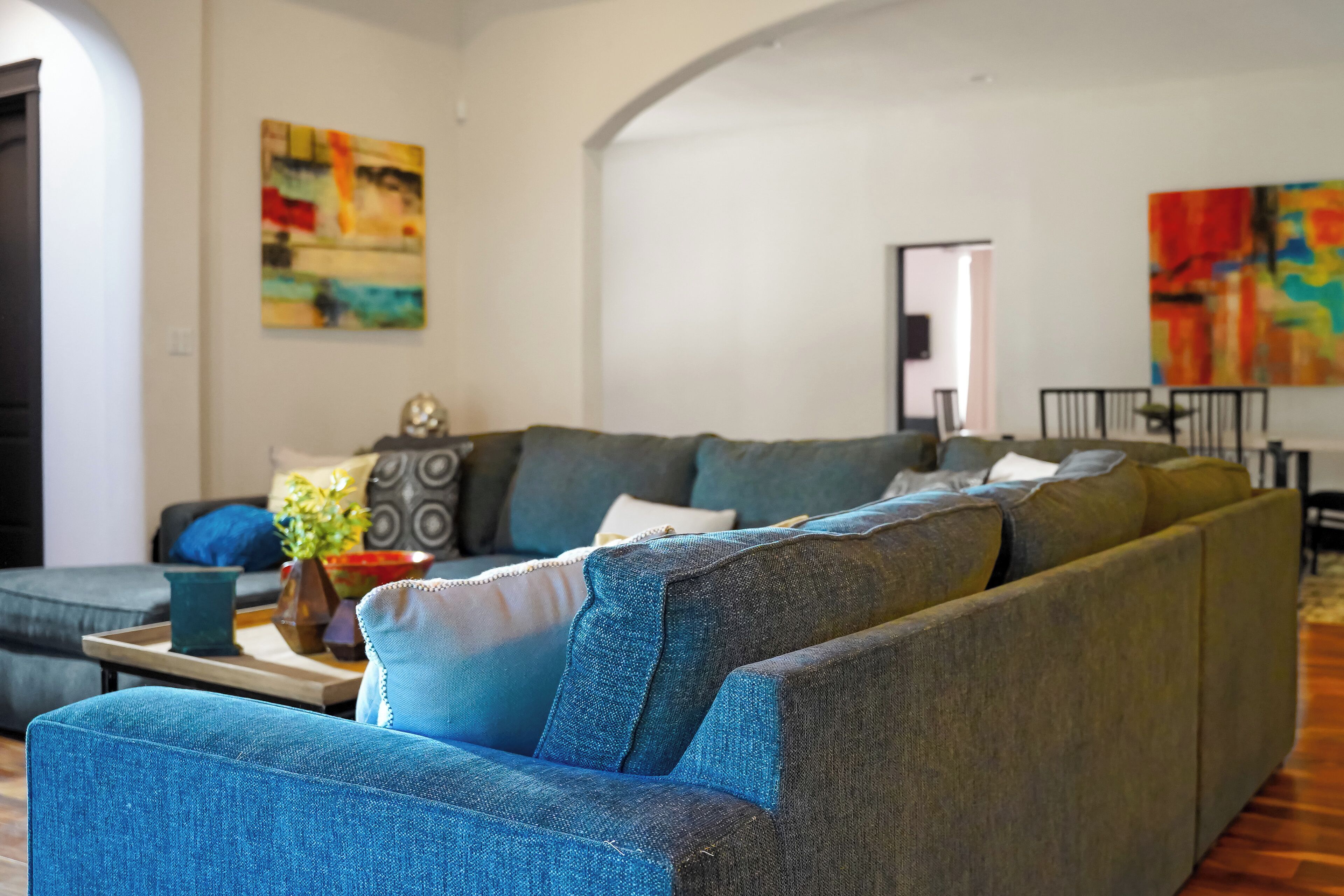 A modern living room with a sectional sofa, a coffee table, and two abstract paintings.