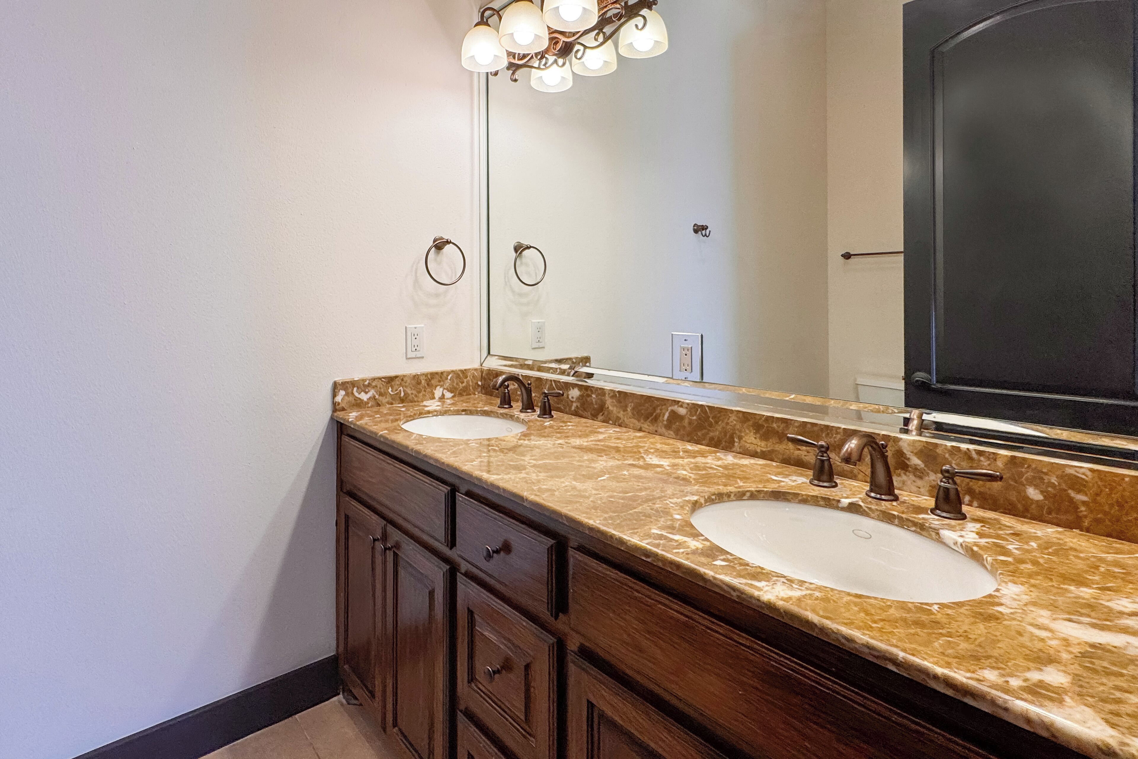Un baño con dos lavamanos, un espejo grande y un mueble tocador con cajones.