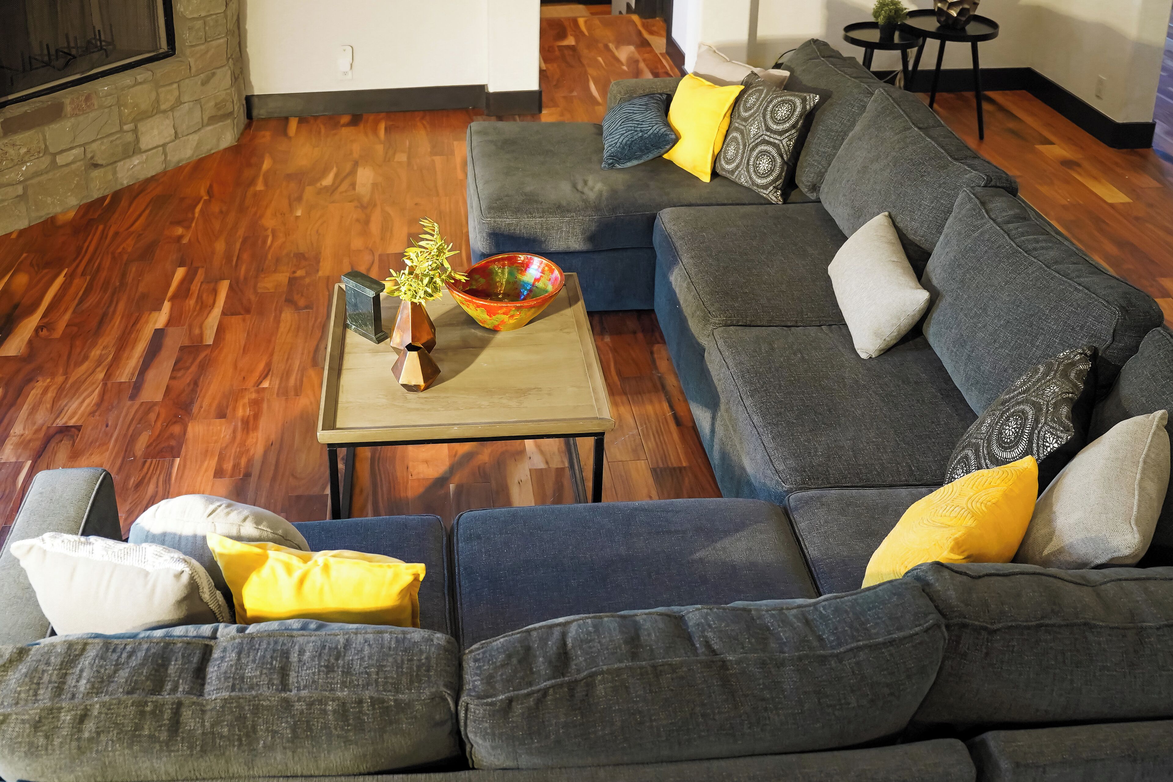 A modern living room with a sectional sofa, a coffee table with a bowl and plant, and a fireplace.