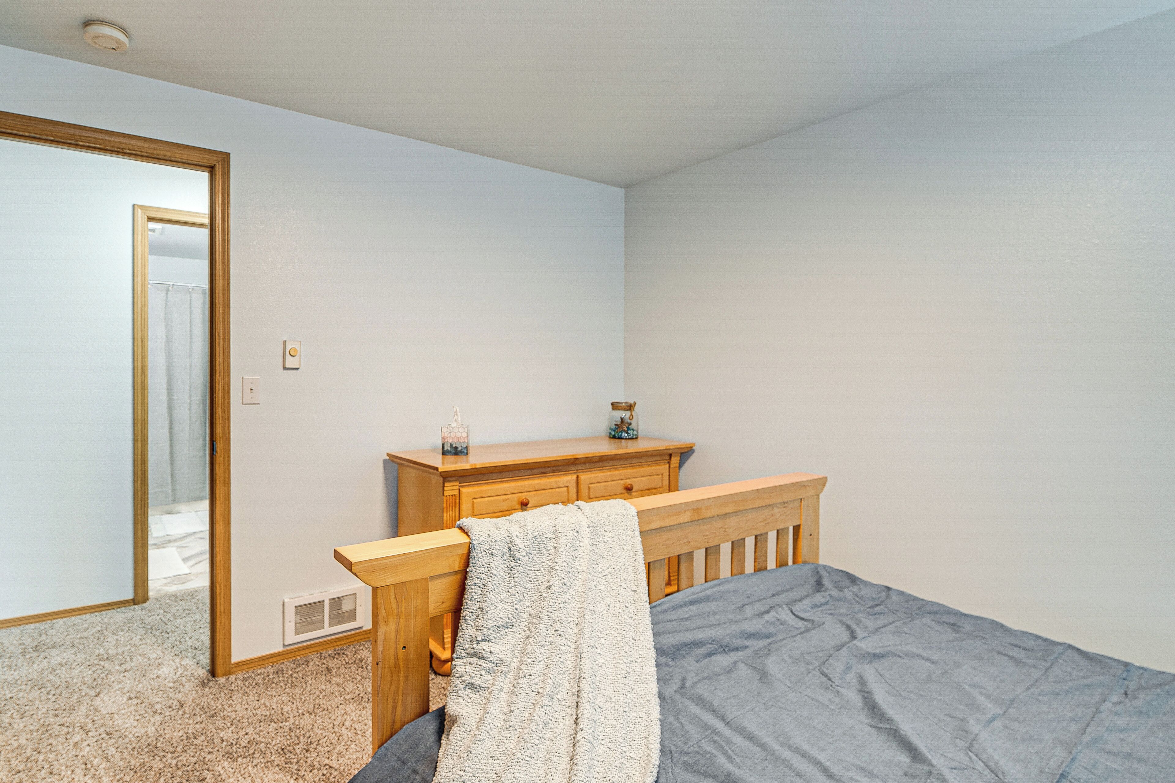 Un dormitorio con cama, cómoda de madera y espejo.
