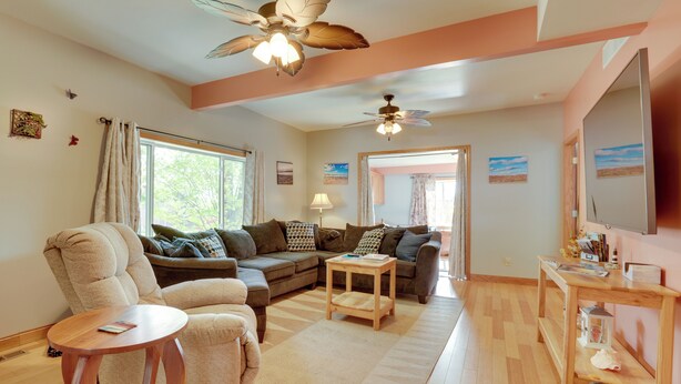 A living room with a sofa, armchair, coffee table, and ceiling fan. - Saugatuck Dunes Getaway: Pets OK, Hot Tub! (Fennville)