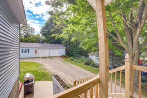 A residential property with a covered porch, a gravel driveway, and a large tree. - Near Saugatuck Dunes: Pet-friendly Home w/ Grill (Fennville)