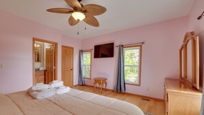 A bedroom with a large bed, a ceiling fan, a television, and a wooden cabinet. - Saugatuck Dunes Getaway: Pets OK, Hot Tub! (Fennville)