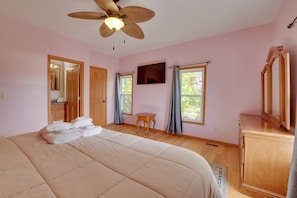 A bedroom with a large bed, a ceiling fan, a television, and a wooden cabinet.