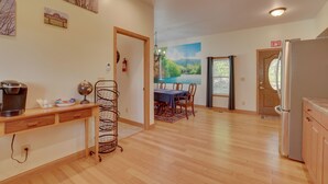 A spacious kitchen with wooden flooring, a dining area with a table and chairs, and a refrigerator. - Saugatuck Dunes Getaway: Pets OK, Hot Tub! (Fennville)