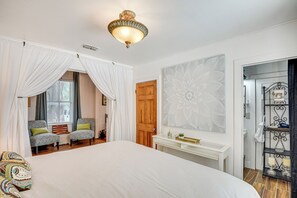 A bedroom with a large bed, two armchairs, a vanity with a mirror, and a decorative wall piece. - Walk to Historic Dtwn: Sanford Home w/ Gas Grill! (Sanford)