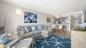 Una sala de estar moderna con un sofá seccional gris, una mesa redonda de centro y un tapete azul con estampado de estrellas.