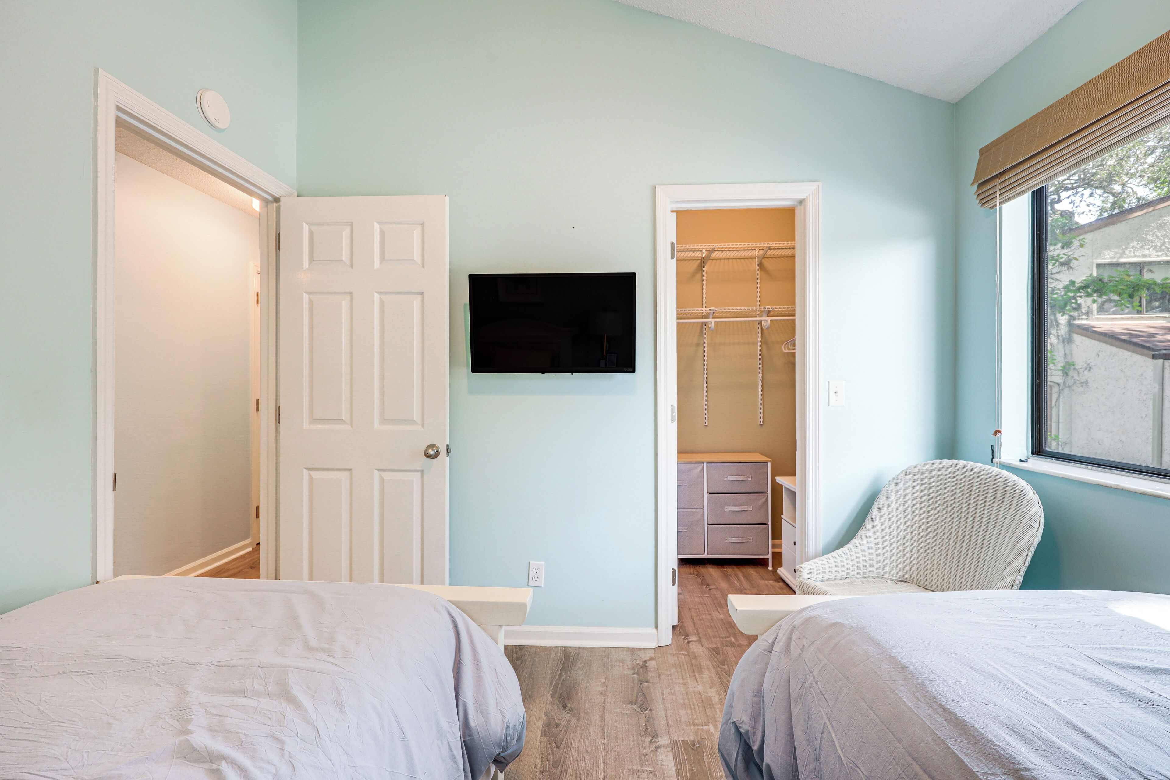A bedroom with two beds, a TV on the wall, and a walk-in closet.