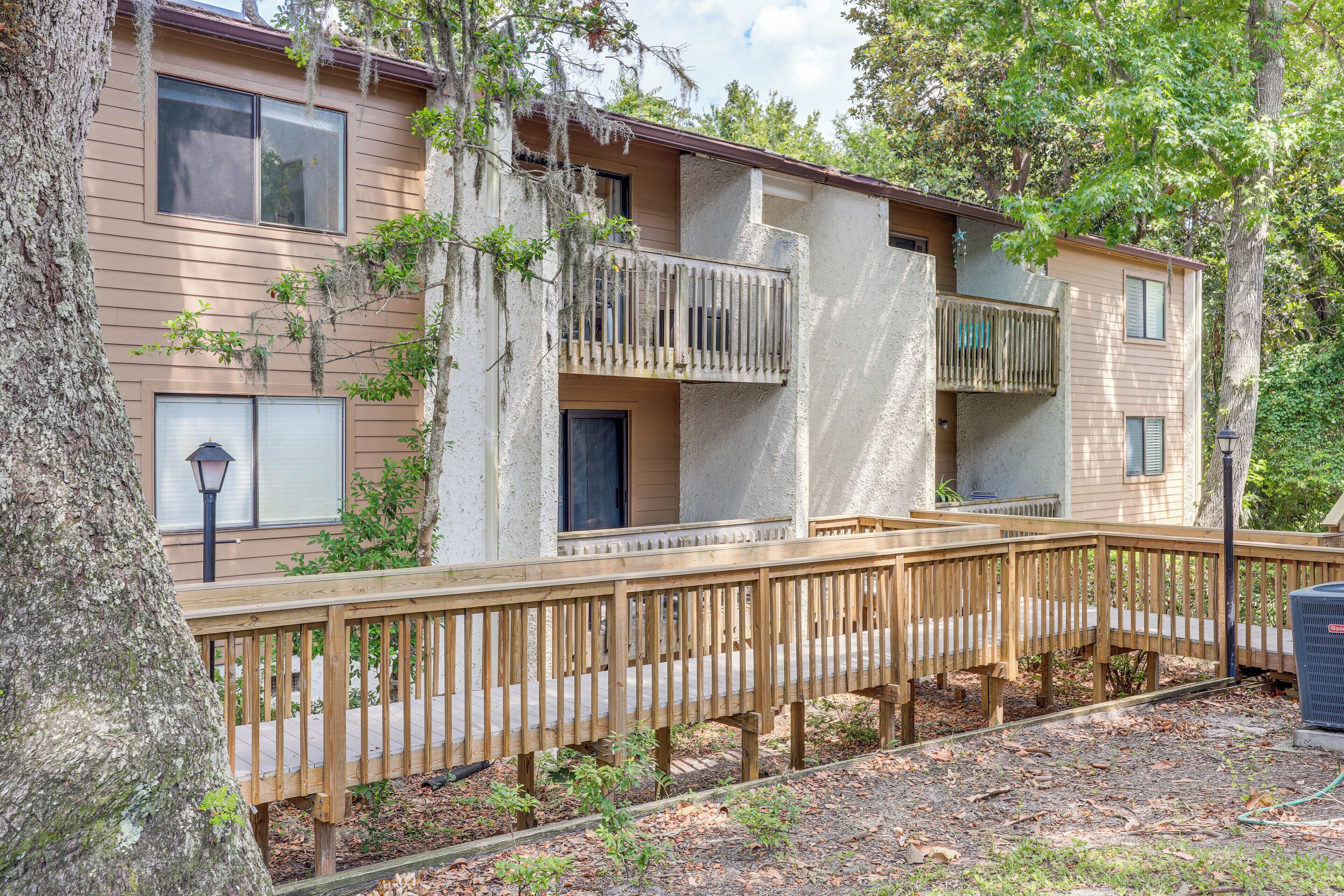 A multi-story building with balconies, a wooden deck, and a small garden area.