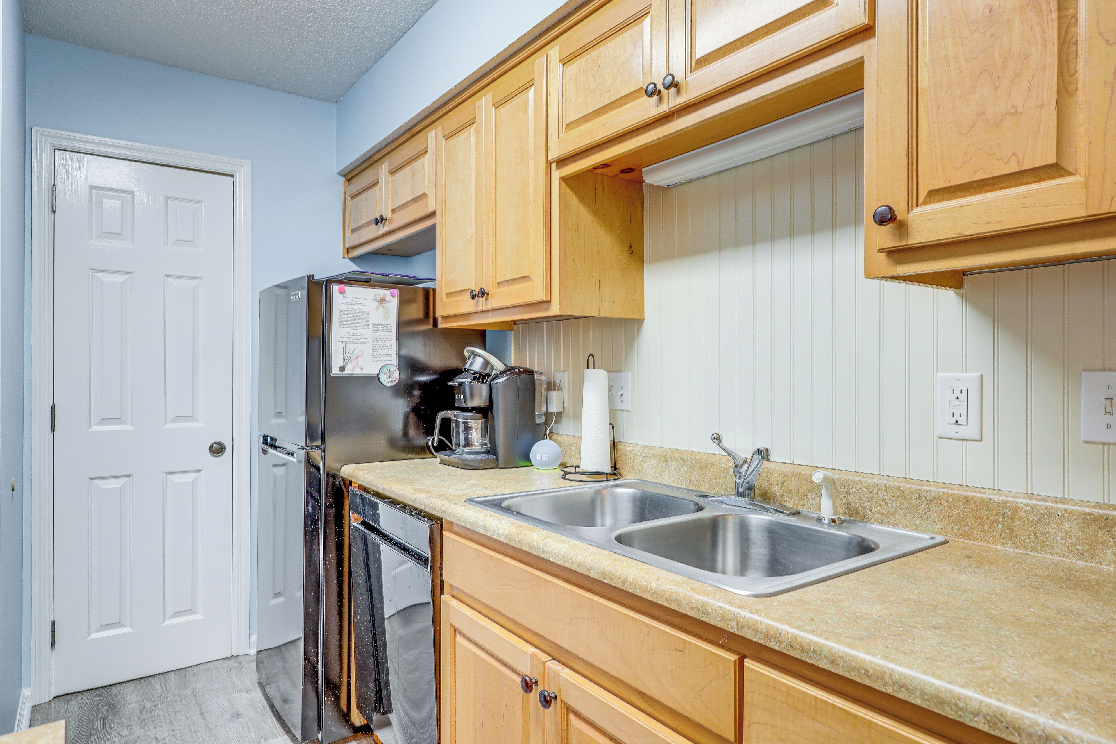 A kitchen with wooden cabinets, a double sink, a refrigerator, and a dishwasher.