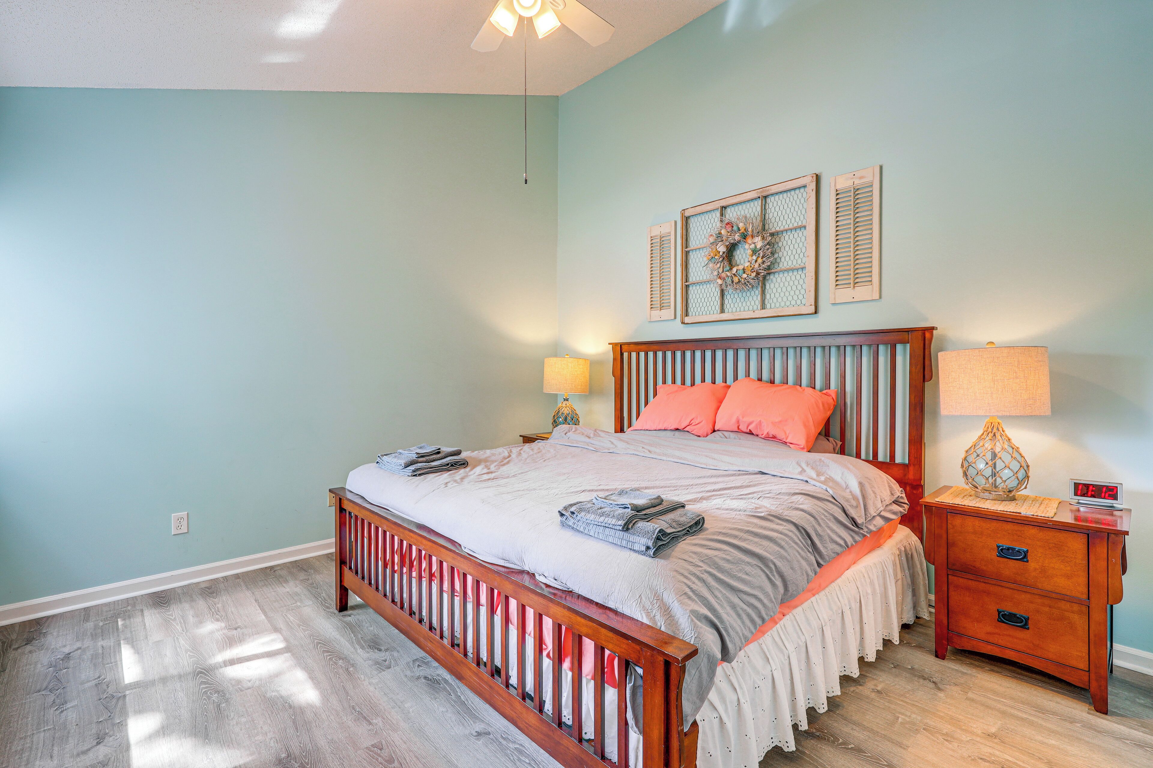 A bedroom with a wooden bed, two nightstands, a ceiling fan, and a wall-mounted light fixture.