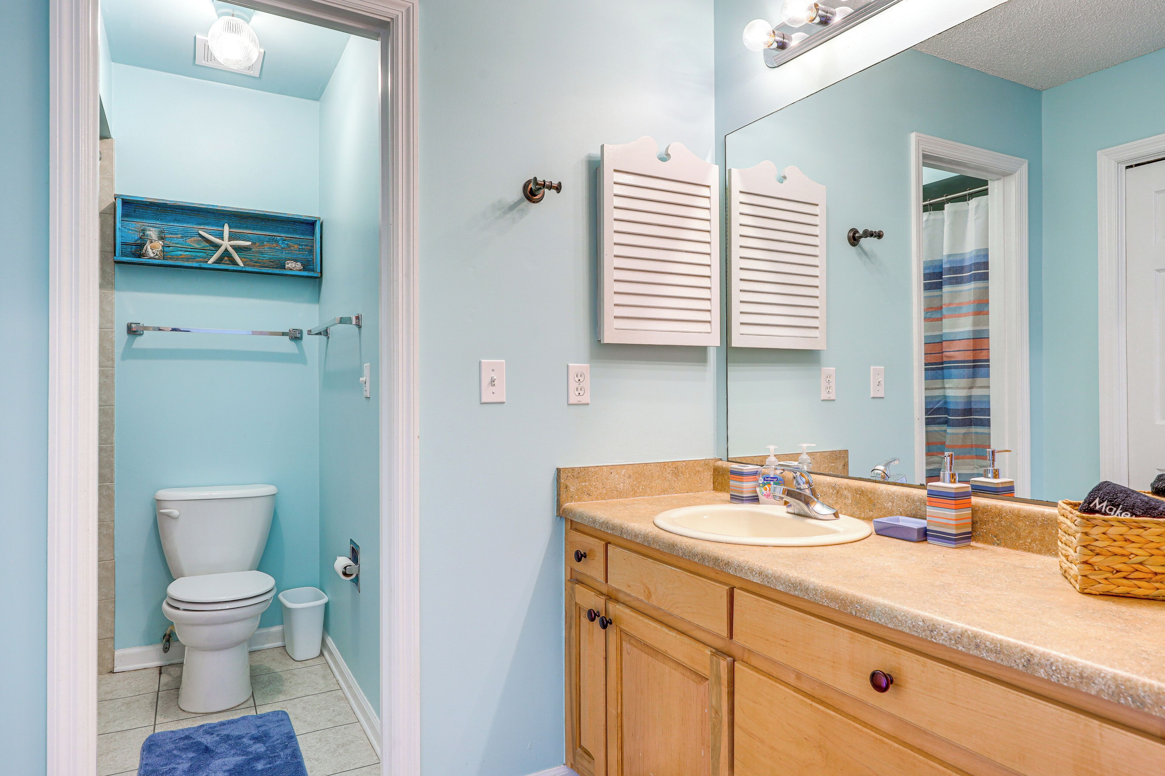 A bathroom with a toilet, sink, and mirror.