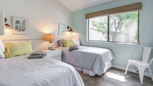 A bedroom with two beds, a nightstand, a chair, and a window with a view of trees. - Amelia Island Condo w/ Pool Access: Walk to Beach! (Fernandina Beach)
