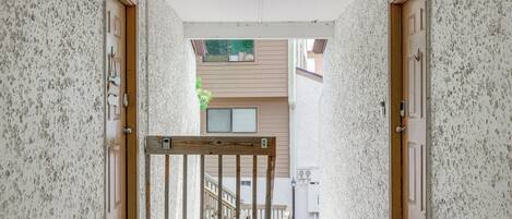 A narrow hallway with a wooden gate leading to a staircase.