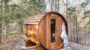Una struttura a forma di botte in legno, con una porta e un asciugamano appeso al manico.