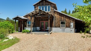 A rustic wooden building with a porch, a red door, and a gravel driveway. - Salt River Access: Mtn-view Star Valley Cabin! (Thayne)