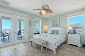 Une chambre à coucher comprenant un lit, un banc, un ventilateur de plafond, une table de chevet et une fenêtre.
