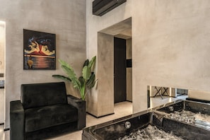 A modern interior with a black sofa, a large potted plant, a painting of a volcano, and a black water feature. - Gallery Home Napoli (Naples)