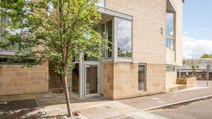 A modern building with a glass entrance, a tree in front, and a paved sidewalk. - Westburn Lane Apartments (No 2) (St Andrews)