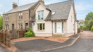 A two-story house with a sloped roof, a front door, and a small front yard. - Kinnessburn Villa (St Andrews)