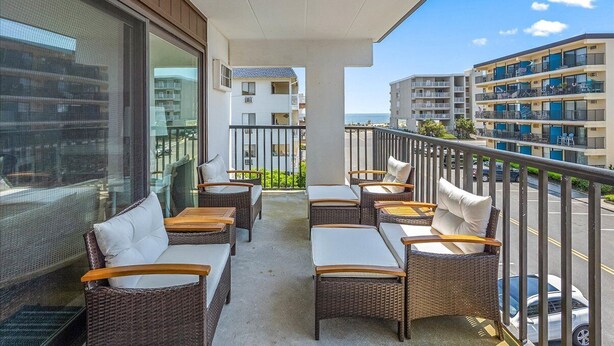 A balcony with wicker furniture and a view of other buildings. - Ocean Block 2 BR Unit Ready for Summer Fun! (Ocean City)