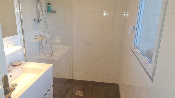 Un baño moderno con ducha, lavamanos y espejo.