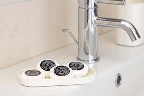 Ein Waschbecken mit einem chromfarbenen Wasserhahn und Seifenspendern.