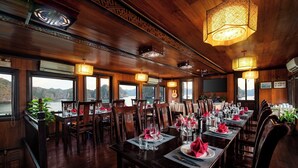 A restaurant with wooden interiors, large windows, and tables set for dining. - Garden Bay Classic  (Bai Chay)