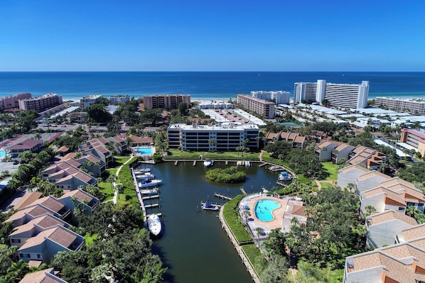 An aerial view of a coastal resort area with a marina, swimming pool, and various buildings.