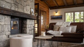 Ein gemütliches Wohnzimmer mit Kamin aus Stein, einem braunen Ledersofa und einem runden Tisch mit Kerze.