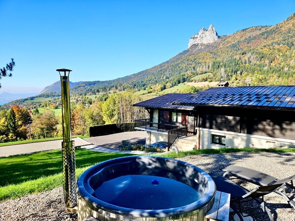 A hot tub with a view of a mountain and a house with a blue roof.