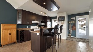 A kitchen with dark wood cabinets, a granite countertop, and a central island with bar stools.