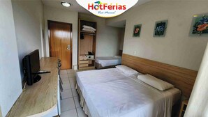 Ein Hotelzimmer mit Bett, Schreibtisch mit Fernseher, Kleiderschrank und einem kleinen Badezimmer.
