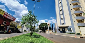 A street view with a building featuring balconies and air conditioning units, a street lamp, and a clear blue sky. - Golden Dolphin Express - HotFérias (Caldas Novas)