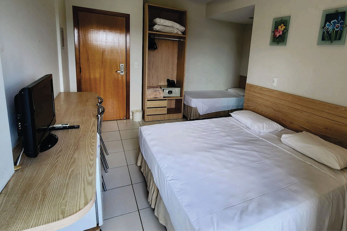 A hotel room with a bed, a desk with a TV, a wardrobe, and a small bathroom.