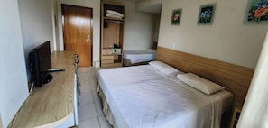 A hotel room with a bed, a desk with a TV, a wardrobe, and a small bathroom. - Golden Dolphin Express - HotFérias (Caldas Novas)