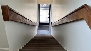 A staircase with wooden handrails and a carpeted floor leading to a door at the top.
