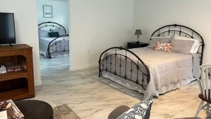 A bedroom with a bed, bedside table, lamp, and a TV.