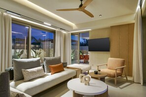 A modern living room with a sofa, armchair, round table, and a ceiling fan.