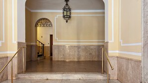 Eine Marmortreppe mit vergoldeten Geländern führt zu einem Eingang mit einem verzierten Bogen.