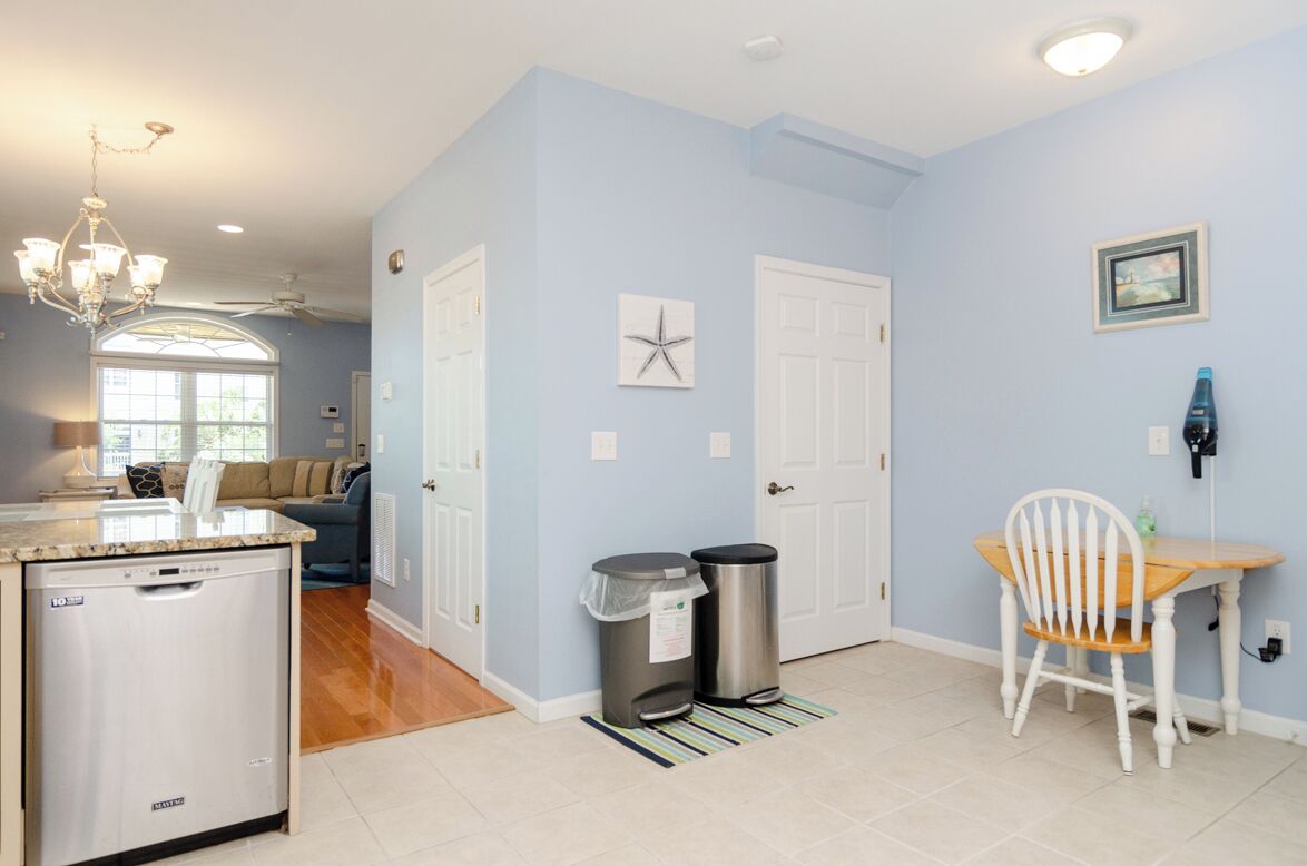 A kitchen with a dishwasher, a dining area with a table and chairs, and a hallway with a starfish decoration.