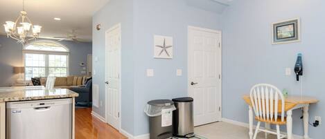 A kitchen with a dishwasher, a dining area with a table and chairs, and a hallway with a starfish decoration.