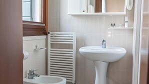 A bathroom with a toilet, bidet, sink, and a mirror above the sink. - STUDIO VENICE GUESTHOUSE (Mogliano Veneto)