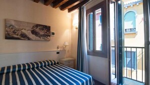 A room with a bed, a painting, a nightstand, a lamp, and a sliding glass door leading to an outdoor area. - STUDIO VENICE GUESTHOUSE (Mogliano Veneto)