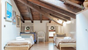 A room with two beds, a chair, wooden beams on the ceiling, and framed pictures on the wall. - STUDIO VENICE GUESTHOUSE (Mogliano Veneto)