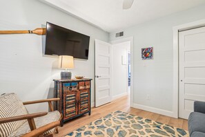 A living room with a television, a patterned rug, a wooden chair, and a cabinet with decorative items. - New Listing -- 3 BR Oceanfront Condo in Duck with pool (Duck)