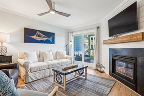 A living room with a sofa, coffee table, fireplace, TV, and artwork.